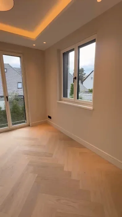 Helle Wand- und Deckenflächen mit indirektem Licht und warmem Parkett.